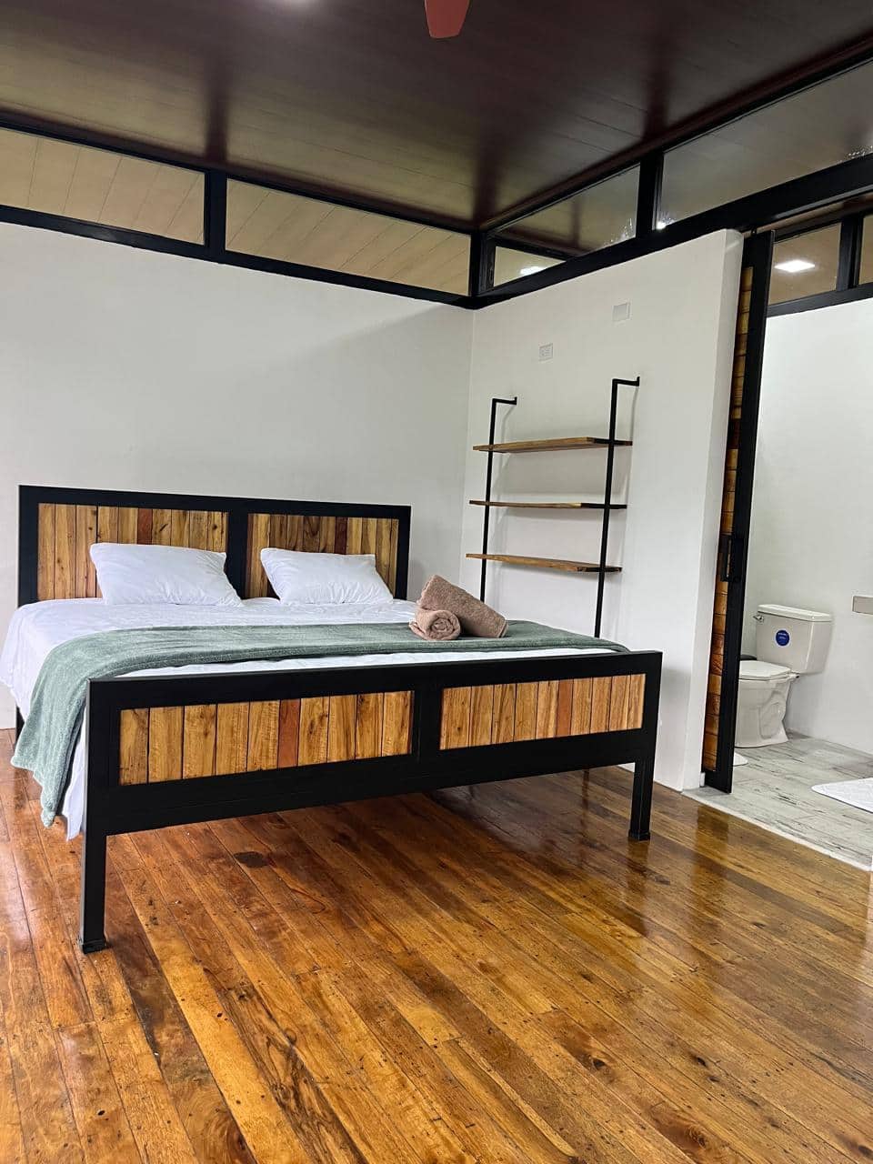 Interior de cabaña con cama de madera, piso de madera y baño propio