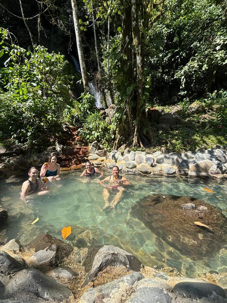 Bañistas en una poza termal natural entre rocas del río